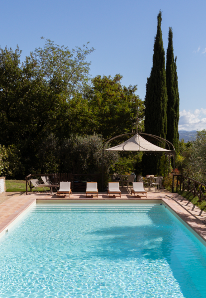 La piscina panoramica con vista su Assisi e Perugia di San Felicissimo tra i cipressi dell'agriturismo